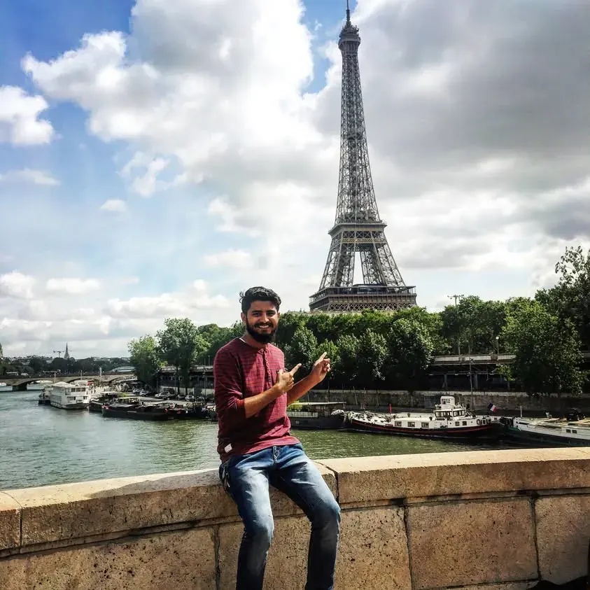 Nikunj by the Seine with the Eiffel Tower behind him