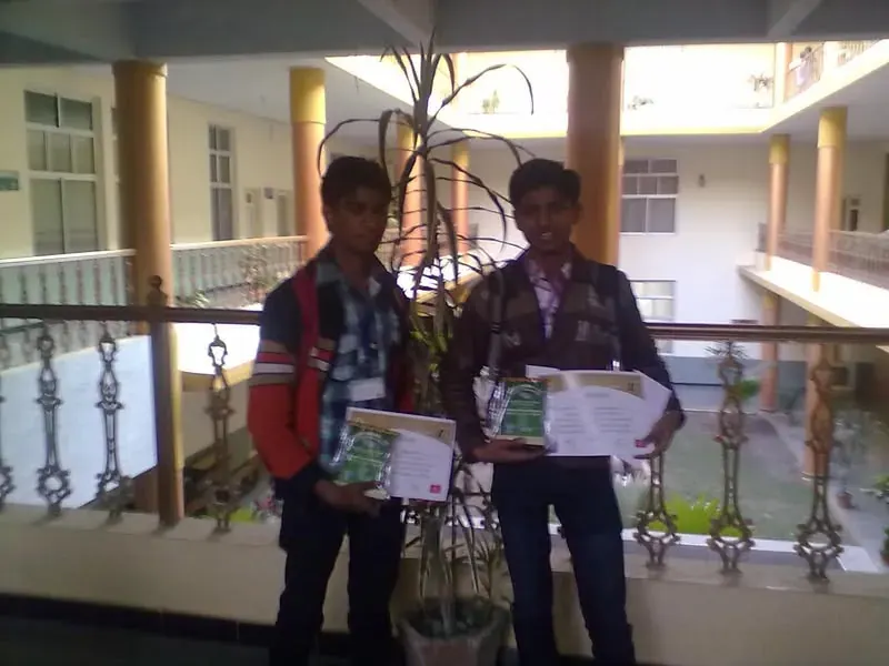 Two students holding prize certificates after a quiz competition
