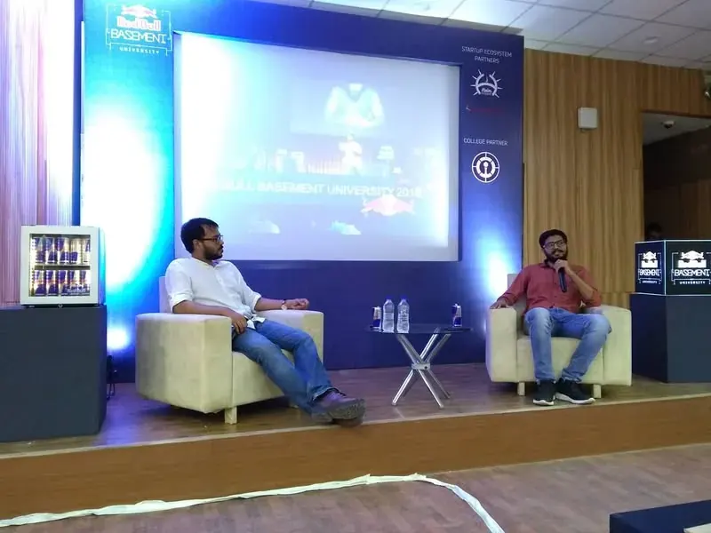 A fireside chat on stage in front of a projector screen
