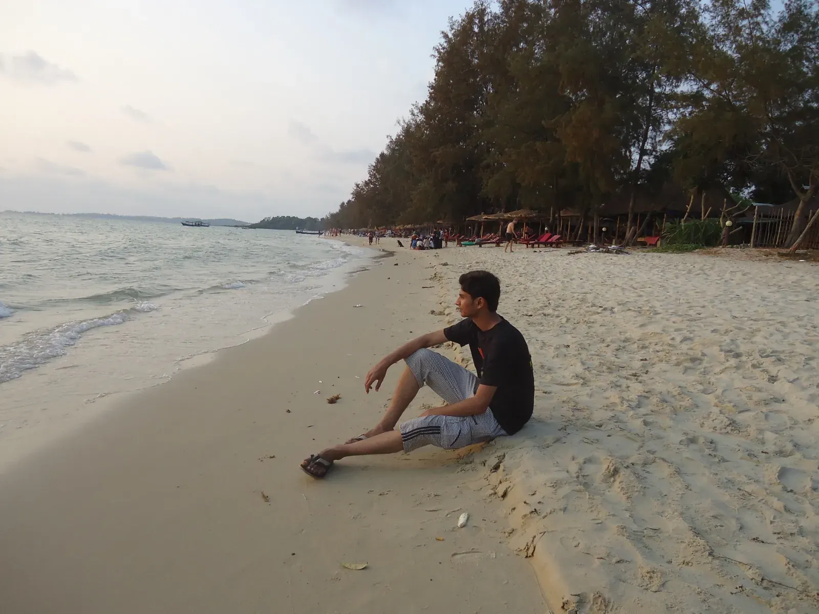 Nikunj sitting on the sand at Otres Beach at dusk