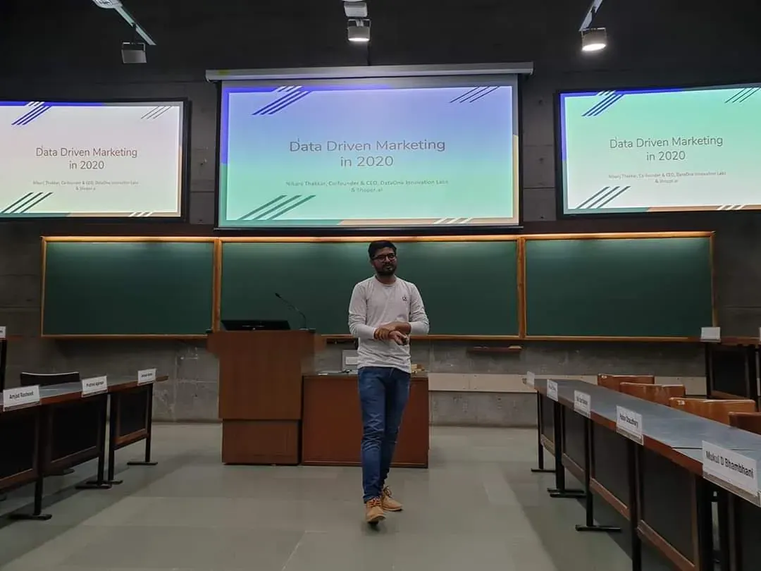 Nikunj speaking at a lectern at IIM Ahmedabad